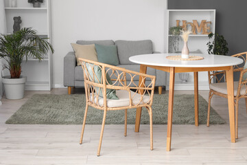 Interior of cozy spacious living room with table, armchairs, comfortable sofa, houseplants and shelving unit