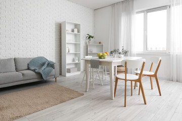 Interior of light room with dining table and sofa