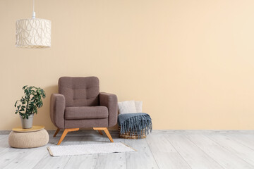 Interior of living room with brown armchair and plant on pouf