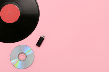 Vinyl, compact discs and USB flash memory on pink background. Concept of evolution