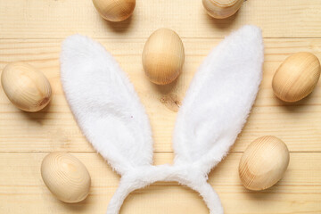 Bunny ears with Easter eggs on light wooden background