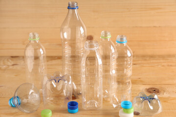 Plastic bottles with caps on light wooden background