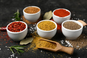 Composition with bowls of different spices on dark background