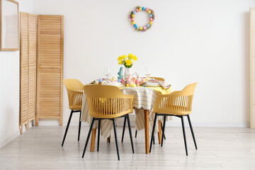 Beautiful table setting with tulip flowers and Easter decoration in dining room
