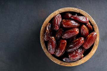 Dried Dates in Wooden Bowl on Dark Background, Top View, Copy Space