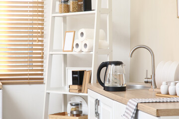 Electric kettle with water near sink on table in kitchen