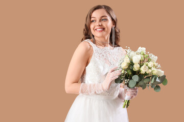 Beautiful bride in white wedding dress with flowers on beige background