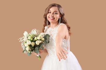 Beautiful bride in white wedding dress with flowers on beige background