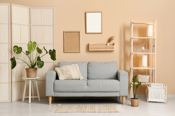 Grey sofa with houseplants, wooden rack and lamps in living room