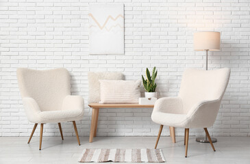 White armchairs with floor lamp, bench and pillows in light room