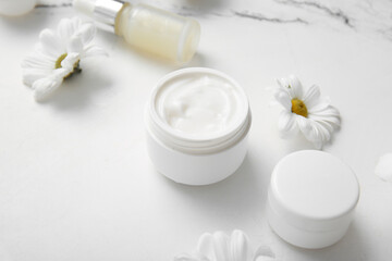 Cosmetic cream, serum and beautiful flowers on light background