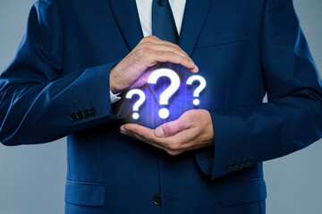 Businessman holding virtual question marks on grey background, closeup