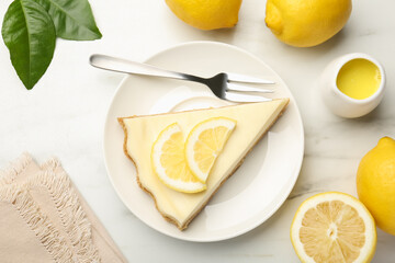 Piece of delicious lemon cheesecake served on white marble table, flat lay