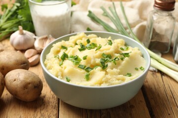 Delicious mashed potato with green onions on wooden table, closeup