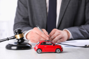 Auto accident law. Man working at table indoors, focus on toy car