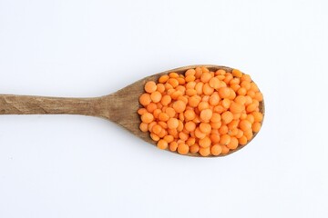 Raw lentils in wooden spoon isolated on white, top view