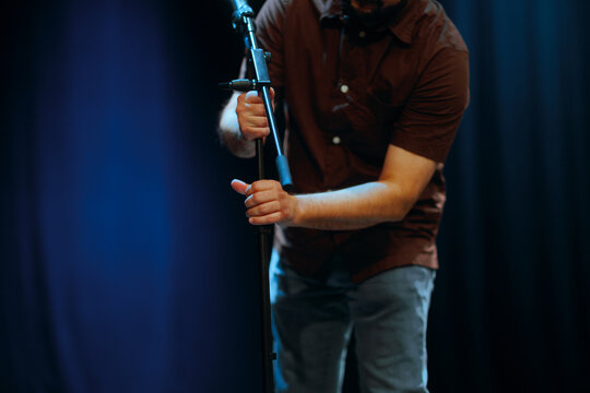 Technician Adjusts and Arranges a Microphone on Stage. Man getting reading before a concert setting up the audio equipment 
