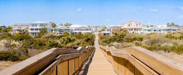 Long wood bridge leading to beach houses on the East Coast during a sunny day with beautiful blue sky