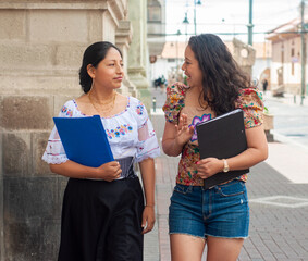 Two women enjoy a leisurely walk in vibrant traditional outfits, sharing thoughts together