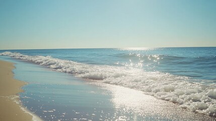 A beautiful beach with waves and shimmering sunlight is visible