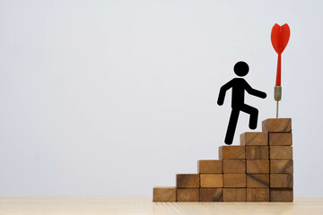 A simplistic illustration showing a figure climbing wooden blocks towards a dartboard, symbolizing...
