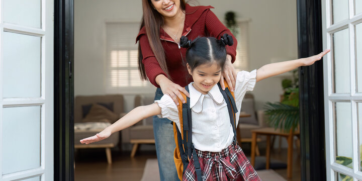 Playful Moment and Carefree Sending Off. A mother supports her daughter in a playful manner as she prepares for school.