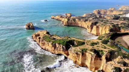 The aerial drone view of golden cliffs and rock formations of the Portugal's southern coast near Albufeira, Algarve, Portugal.