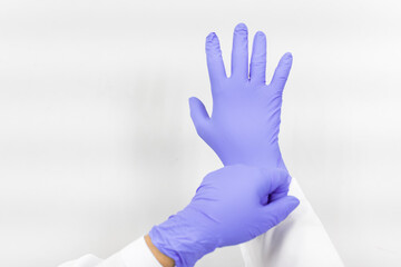 Woman doctor putting blue latex medical gloves on white background.Surgeon wearing gloves before surgery at operating room.Risk and infection control concept