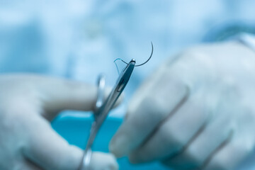 Doctor hand wear sterile gloves and surgery scissor stitching up wound after surgery.Plastic...