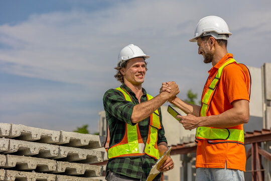 Two Caucasian engineers have handshake to celebrate a successful deal in a precast factory. Expression of cooperation between two civil engineers through handshake in a construction factory