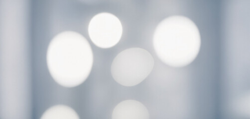 Image shows an abstract background with several out of focus white light spots on a gray surface. Premium modern bokeh photos for poster, banner and print backgrounds.