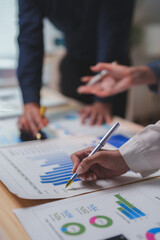 Business team analyzing financial charts and graphs, pointing at statistics and discussing company strategy during a meeting, working together on market research and investment planning