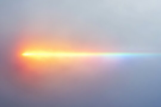 A blurry image of a sunset or sunrise with a rainbow-like effect across the sky.