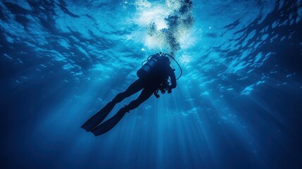 Fototapeta premium Diver silhouette swims in deep blue ocean, sunlight streaming through the surface. Illustrates underwater exploration, adventure, or marine conservation efforts.