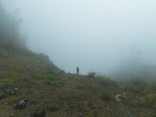 Obraz premium A man walks alone on a foggy hillside
