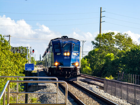 An arriving tri rail train engine RTA South Florida Regional Transportation Agency in Boca Raton, Florida a Miami suburb with palm trees clear day
