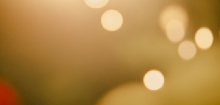 Blurred image of multiple round bokeh lights in various sizes, creating a warm and soft glow against a golden background.