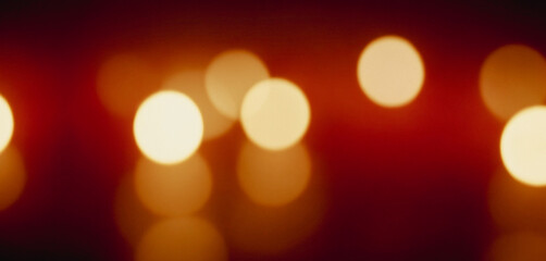 Soft, abstract photograph of out-of-focus golden lights against a warm red-orange background. Elegant bokeh photos for romantic backgrounds with soft and beautiful colors.