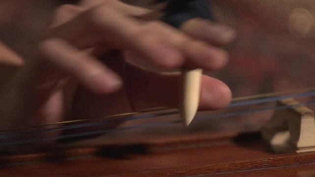 Big close-up of a woman's hand wrapped with gear for playing a Thai musical instrument called the 'Chakhe'.