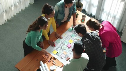 Top view of skilled business team planning and looking blueprint. Group of smart business people working together discussing and talking about building construction while looking at tablet. Symposium.