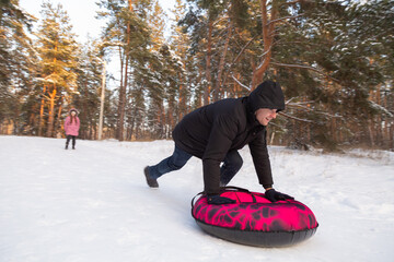 Father and daughter having fun with snow tube in the forest
