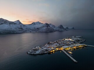 Husøy auf der Insel Senja in Norwegen bei einsetzender Dunkelheit mit leuchtenden Häusern im...