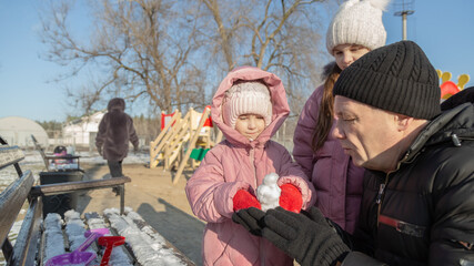 Grandfather playing with her granddaughters on the playground in the park in winter