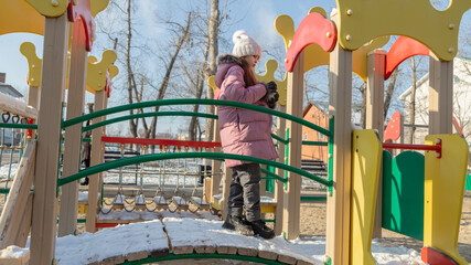 little girl playing on the playground on a winter day