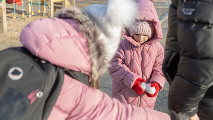 Grandfather walks with his granddaughters after school in the park in sunny winter day
