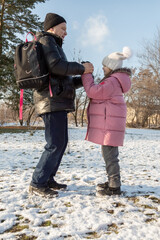 Grandfather walks with his granddaughters after school in the park in sunny winter day