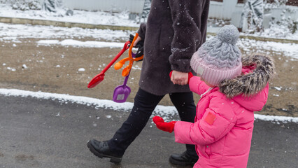 Grandmother walks with her granddaughter along a snowy street in winter