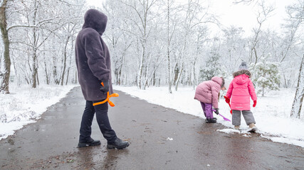 Grandmother with granddaughters on snowy weather outdoors.