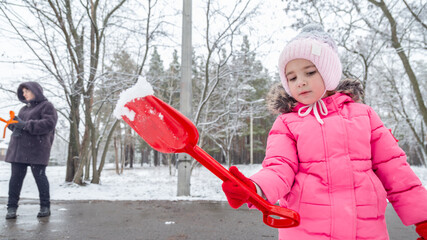 Two little girls playing in a snowy park in winter
