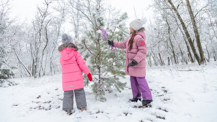 Two little girls playing in a snowy park in winter